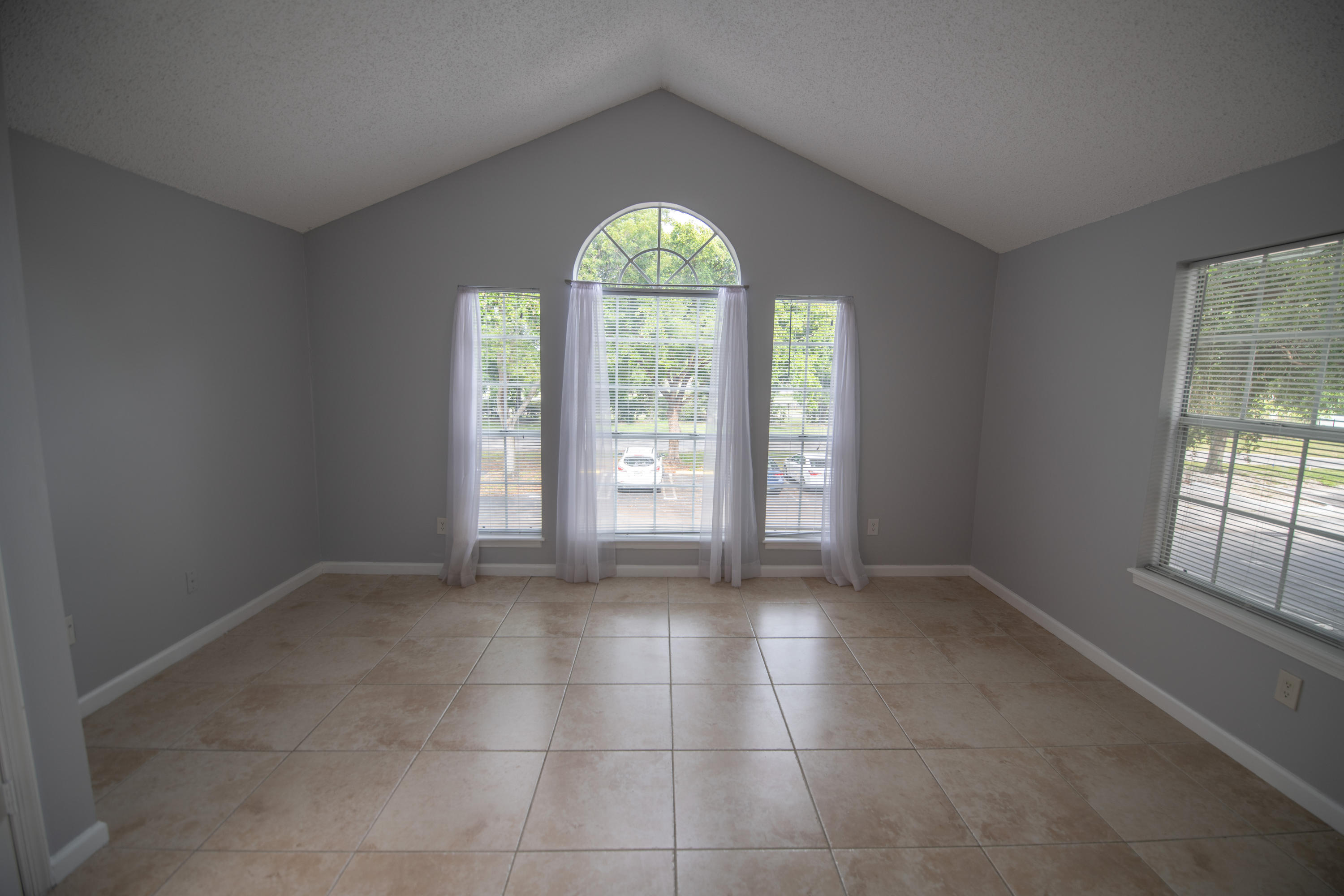1165 Crystal Way, Unit B Delray Beach, FL 33444 - Photo 8 of 27 an empty room with windows and chandelier fan