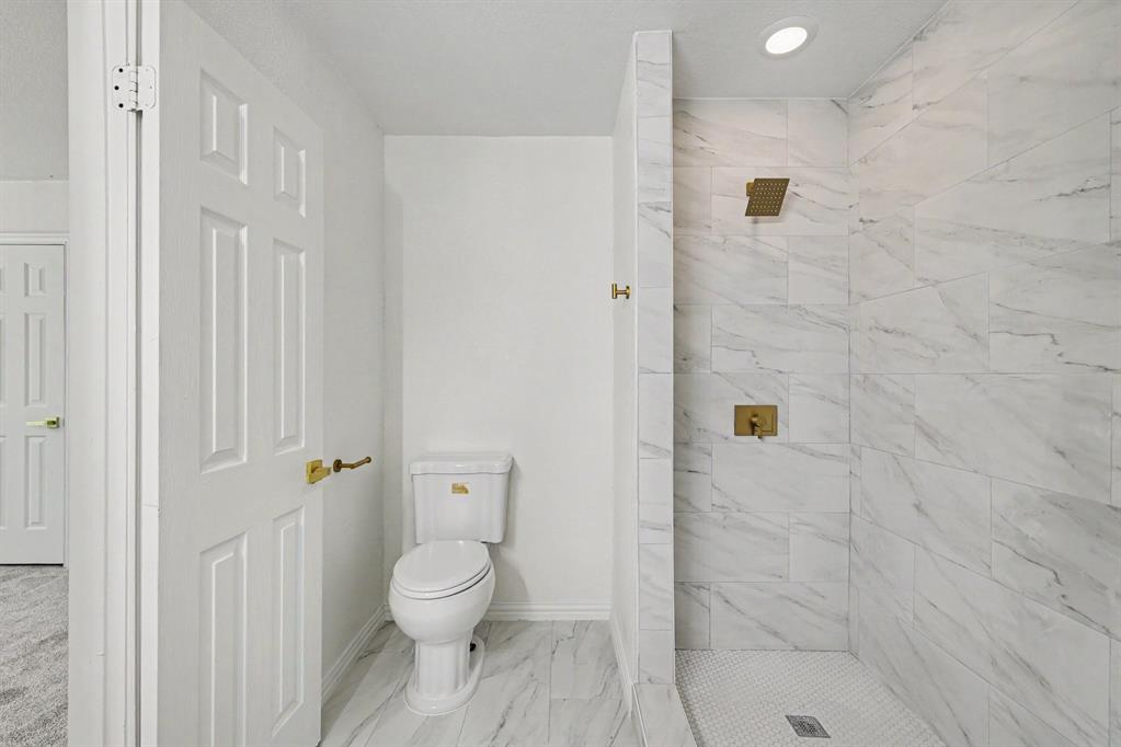 307 Dixon Street Terrell, TX 75160 - Photo 18 of 32 Bathroom featuring a walk-in shower with large format marble-look tile, a rain showerhead, and gold-finish fixtures