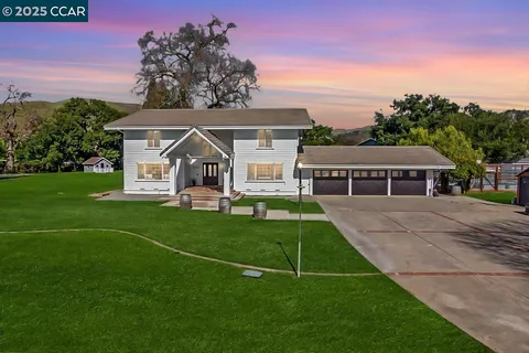 a view of a house with a big yard plants and large trees