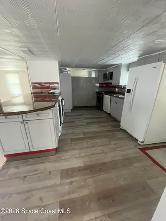 a view of a kitchen with wooden floor and electronic appliances