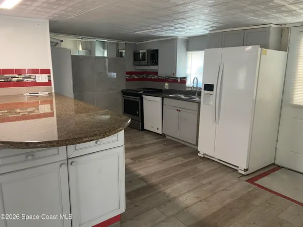 a kitchen with stainless steel appliances granite countertop a refrigerator a stove and a sink