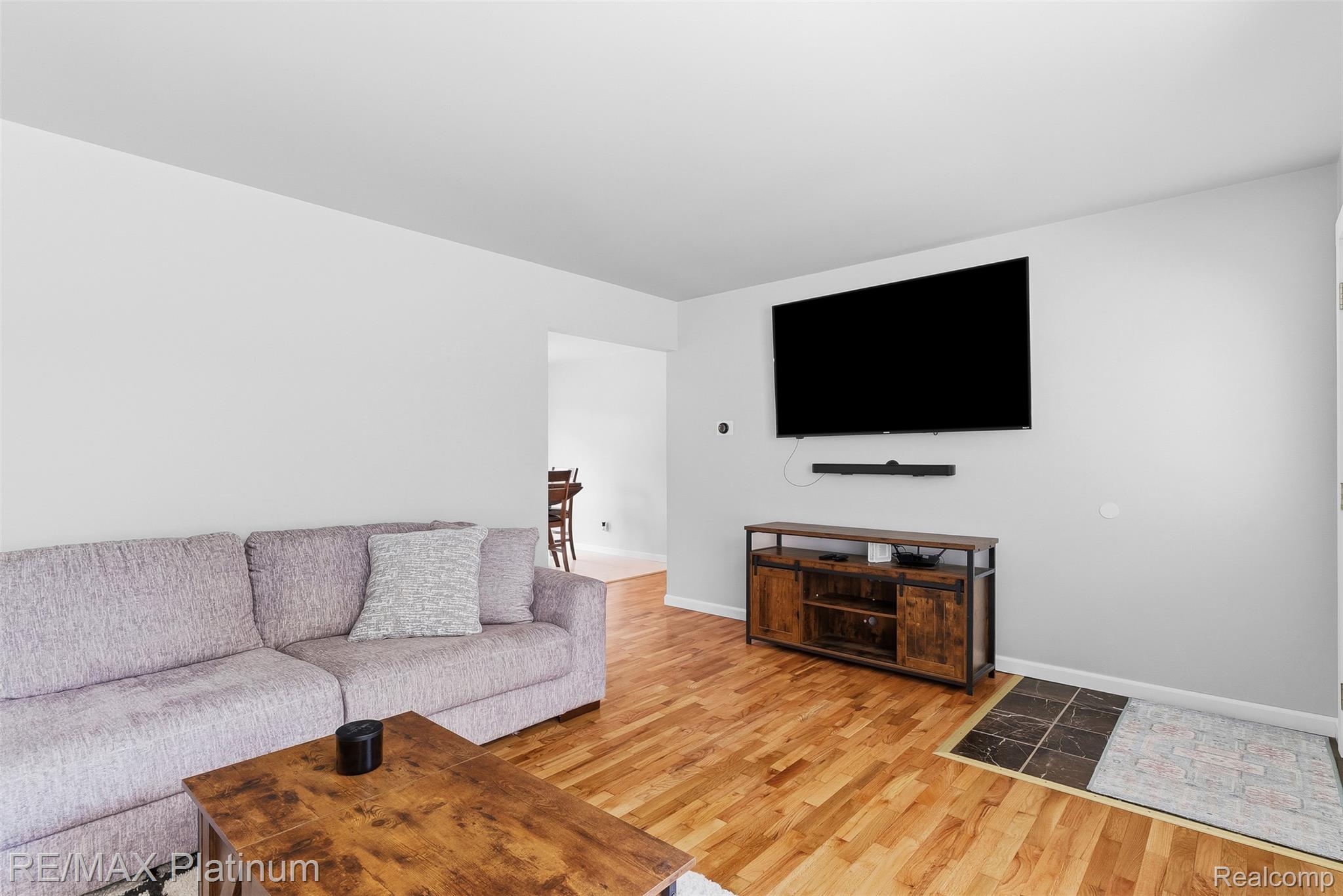 8370 West Rolston Road Linden, MI 48451 - Photo 7 of 36 Spacious living area featuring light wood-finish flooring, a wall-mounted entertainment system, and a tiled entryway