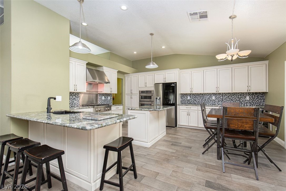 4670 Los Rancheros Avenue Las Vegas, NV 89129 - Photo 5 of 57 Granite countertops and white cabinetry enrich this spacious kitchen with a central island and dining area.