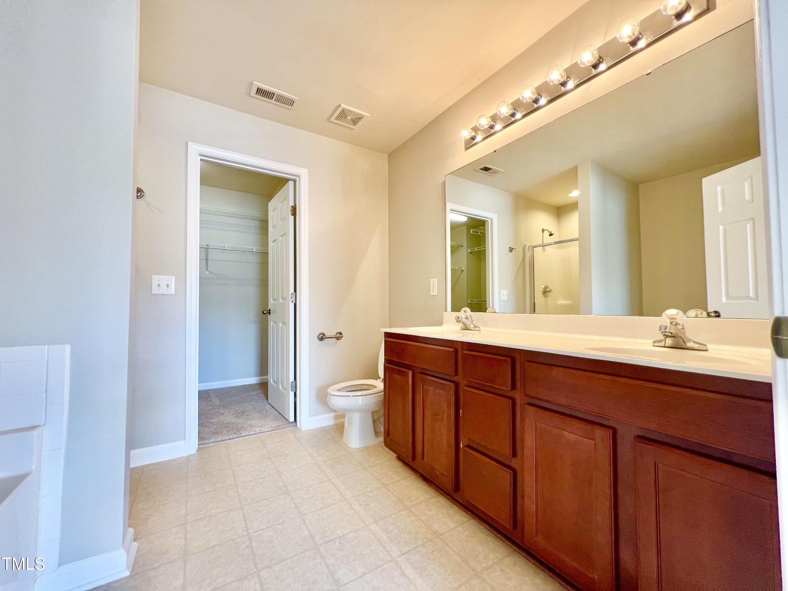 2118 Kedvale Avenue Raleigh, NC 27617 - Photo 11 of 17 a spacious bathroom with a double vanity sink a large mirror and a shower