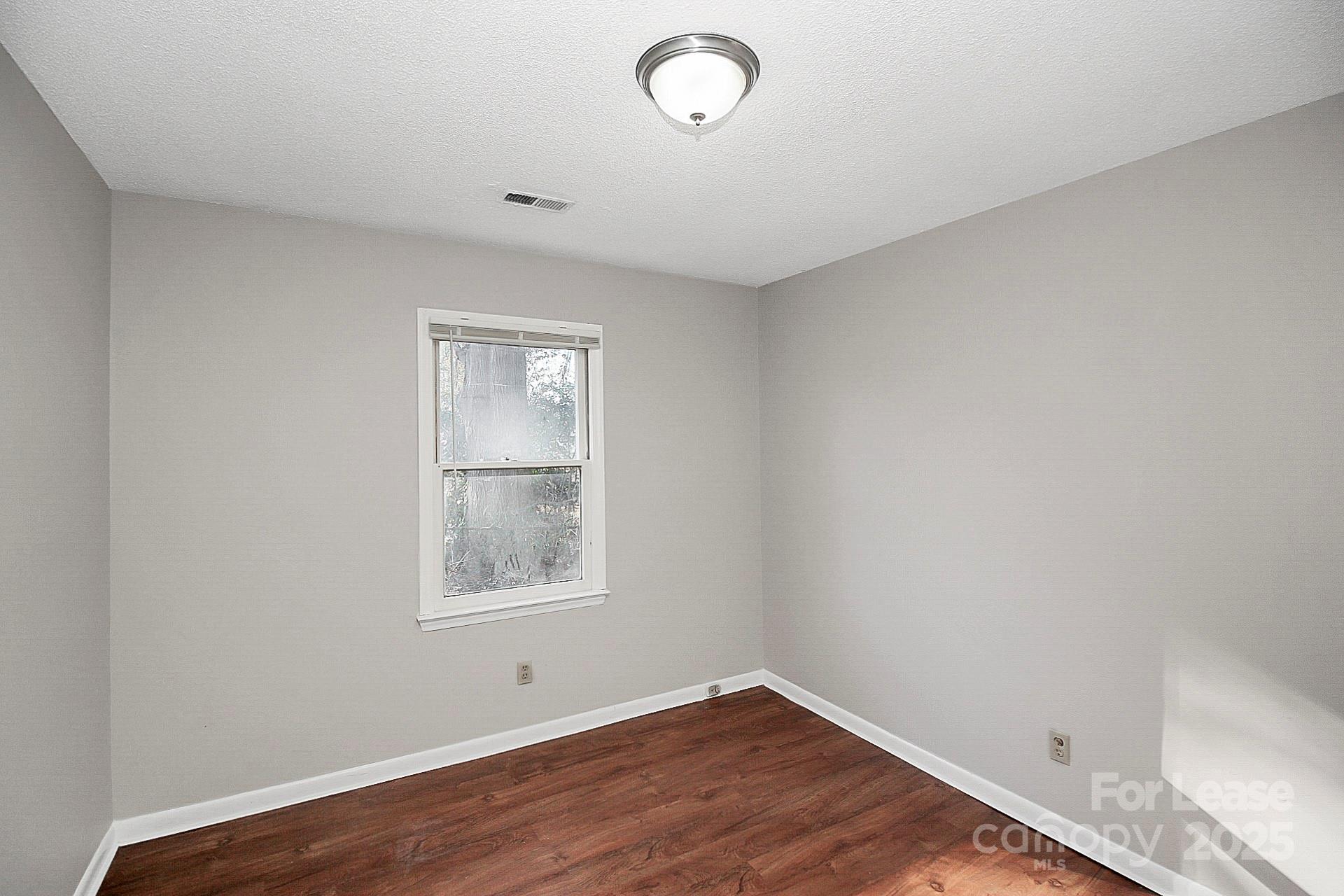 501 North Ransom Street, Unit C Gastonia, NC 28052 - Photo 14 of 19 a view of an empty room with wooden floor and a window