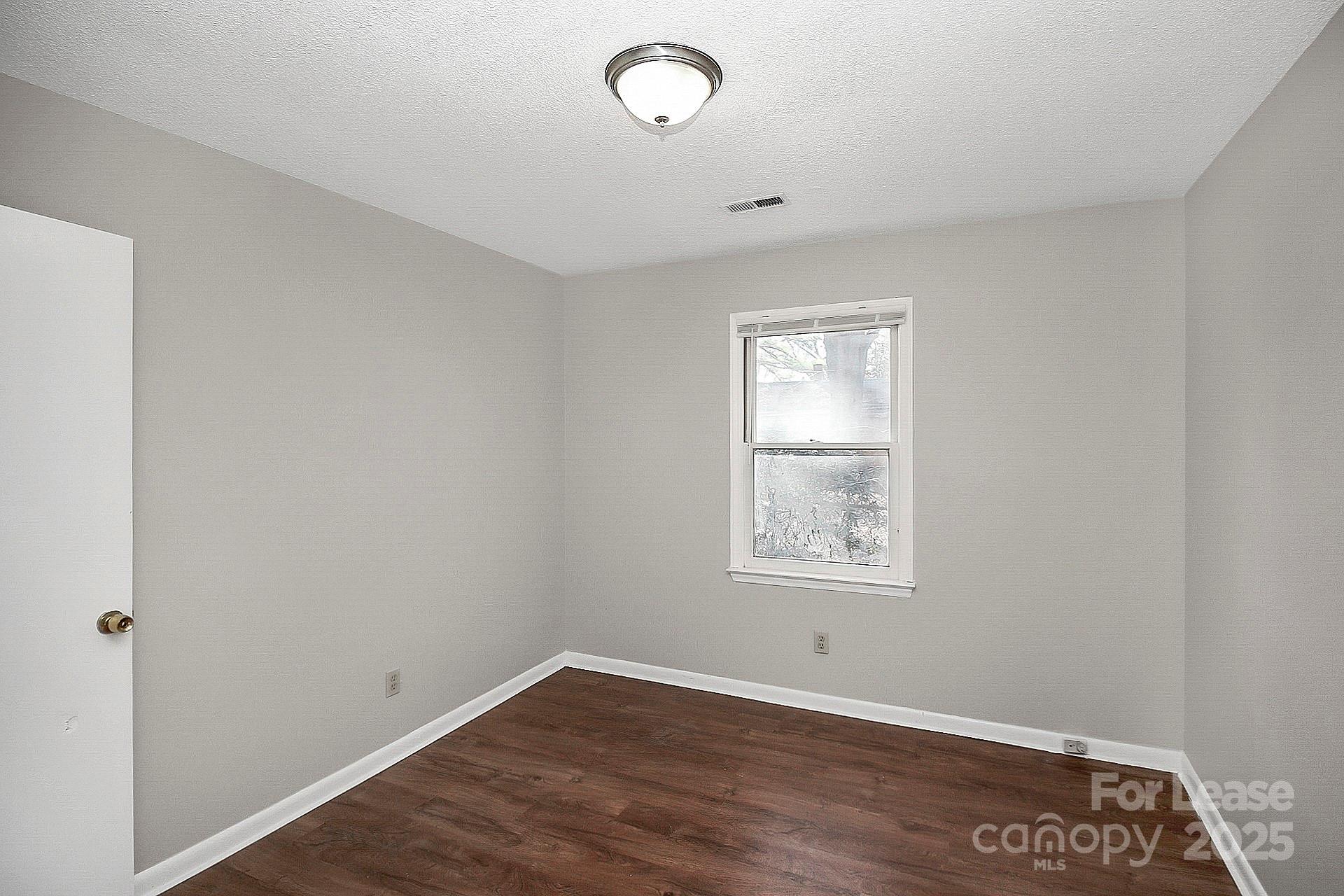 501 North Ransom Street, Unit C Gastonia, NC 28052 - Photo 17 of 19 an empty room with wooden floor and windows