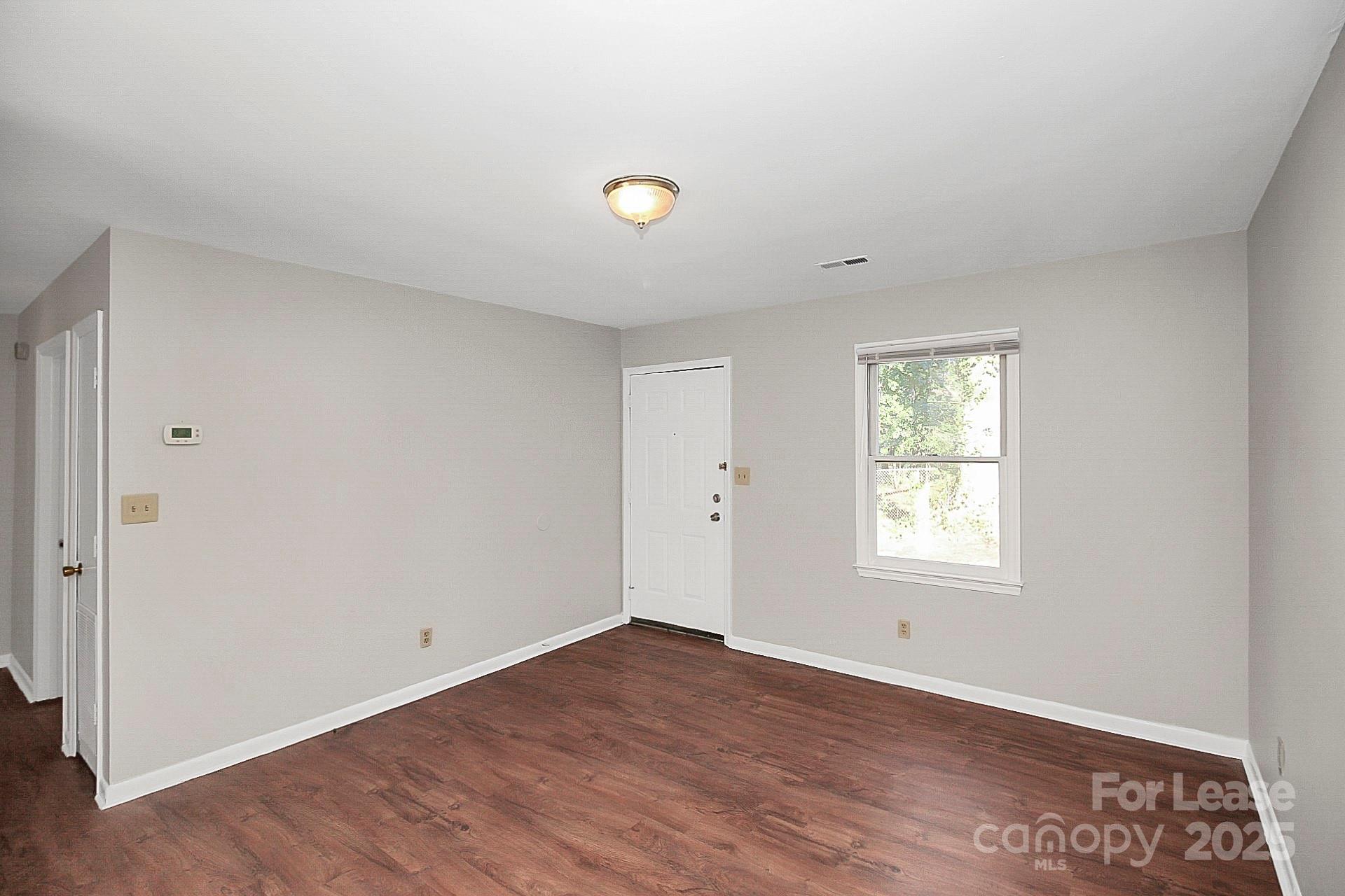 501 North Ransom Street, Unit C Gastonia, NC 28052 - Photo 3 of 19 an empty room with wooden floor and windows
