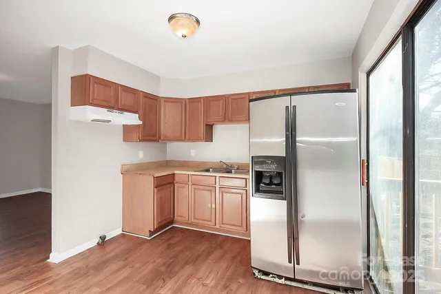 a kitchen with stainless steel appliances granite countertop a refrigerator a stove and a sink with wooden floor