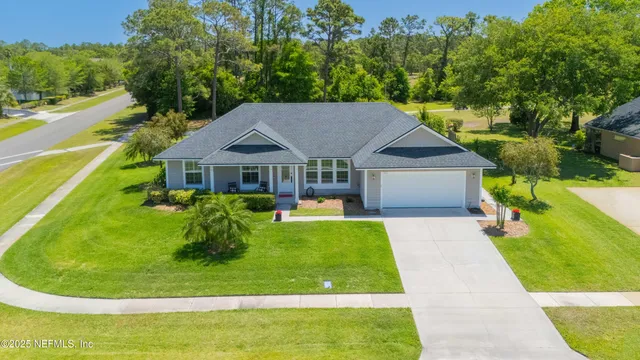 a view of a white house with a big yard and potted plants