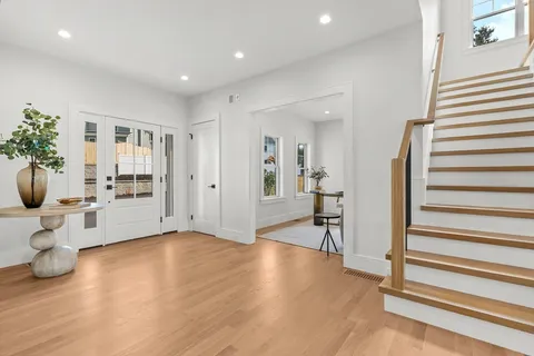 a view of an empty room with wooden floor and stairs