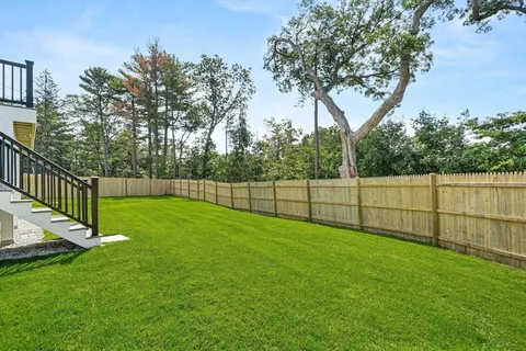 a view of a backyard with a fence and trees