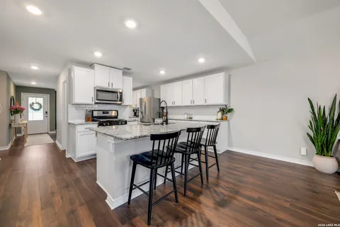 a kitchen with kitchen island granite countertop wooden floors and white appliances