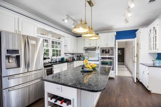 a kitchen with stainless steel appliances granite countertop a refrigerator a oven and a sink