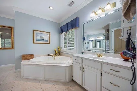 a bathroom with a double vanity sink mirror and bathtub