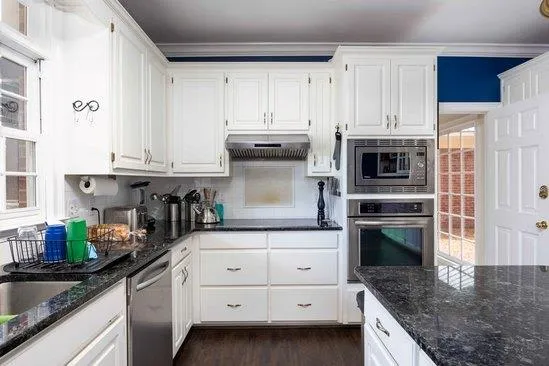 a kitchen with granite countertop a sink a stove and cabinets