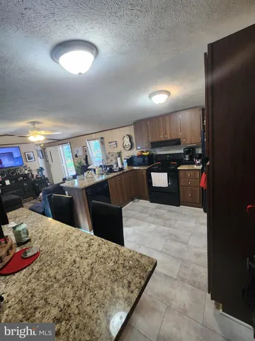 a kitchen with stainless steel appliances kitchen island granite countertop a sink dishwasher stove and refrigerator