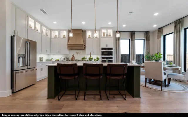 a kitchen with stainless steel appliances kitchen island granite countertop a table chairs and a refrigerator