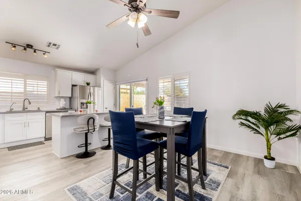 a kitchen with stainless steel appliances a refrigerator a stove a sink dishwasher a dining table and chairs with wooden floor