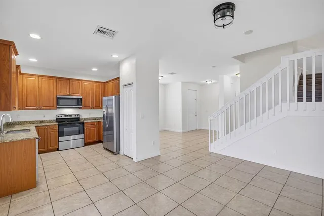 a kitchen with stainless steel appliances kitchen island granite countertop a refrigerator and a stove top oven