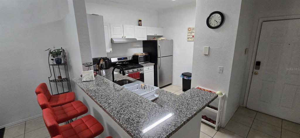 3379 South Kirkman Road, Unit 1015 Orlando, FL 32811 - Photo 6 of 9 a kitchen with stainless steel appliances granite countertop a sink refrigerator stove and white cabinets