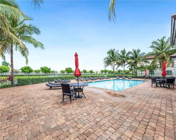 a view of a swimming pool with a lounge chair and palm trees