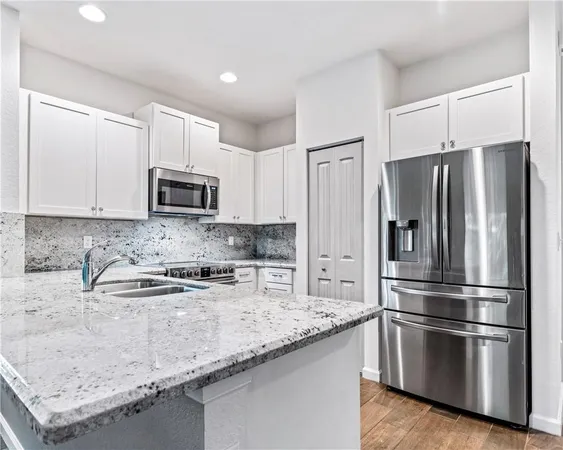 a kitchen with stainless steel appliances granite countertop a refrigerator sink and microwave