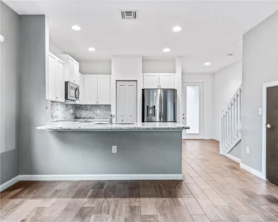 a view of kitchen with stainless steel appliances granite countertop cabinets and wooden floor