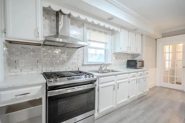 a kitchen with stainless steel appliances white cabinets and a stove a sink