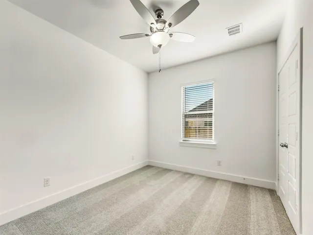 an empty room with a window and a ceiling fan