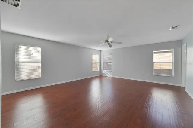 a view of an empty room with wooden floor and window