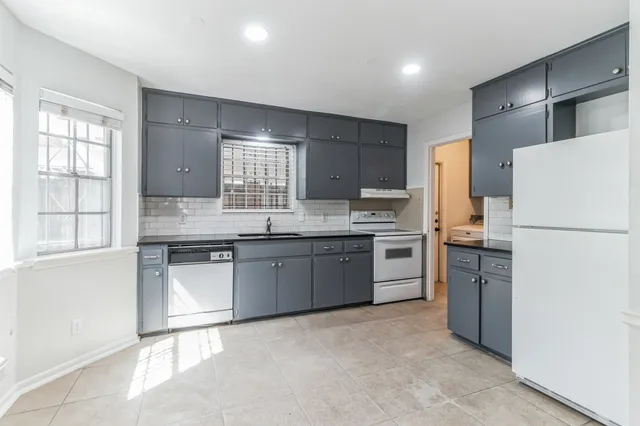 a kitchen with refrigerator a sink and white cabinets