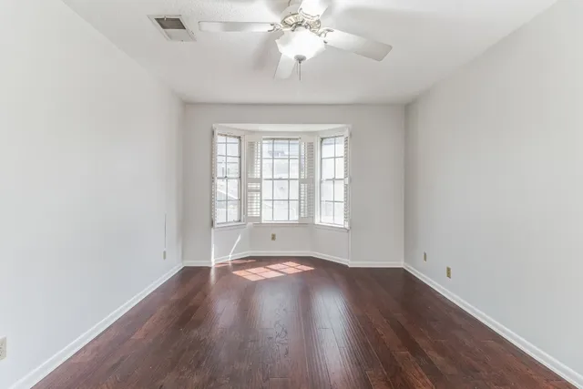 an empty room with wooden floor and a ceiling fan