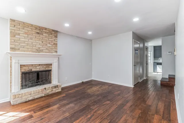 a view of an empty room with wooden floor and a fireplace