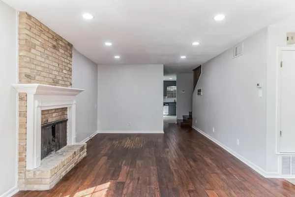 an empty room with wooden floor chandelier fan and windows