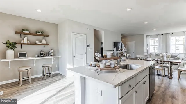 a living room with stainless steel appliances kitchen island granite countertop a sink and chairs