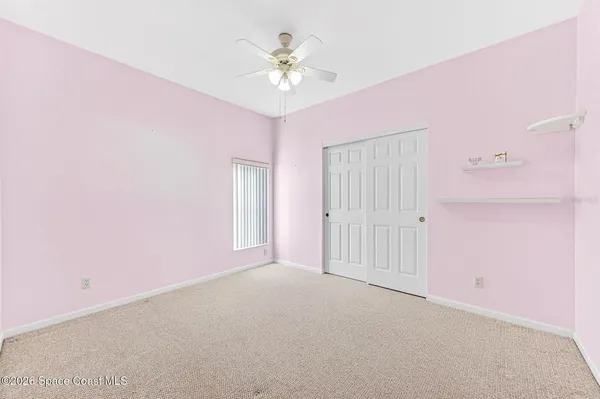 a view of an empty room with chandelier fan