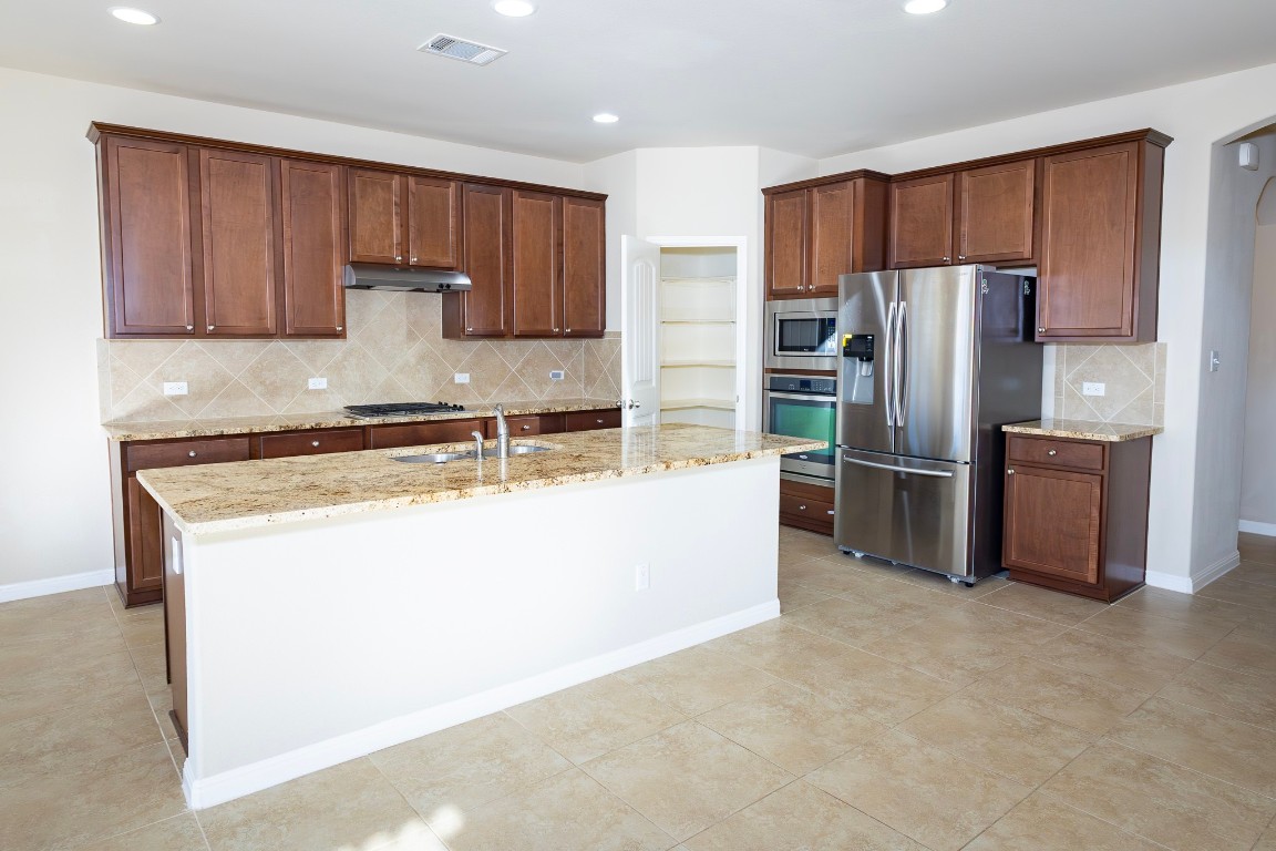 108 Mark Brooks Cove Round Rock, TX 78664 - Photo 9 of 24 a kitchen with stainless steel appliances granite countertop a refrigerator a stove a sink a oven with wooden cabinets