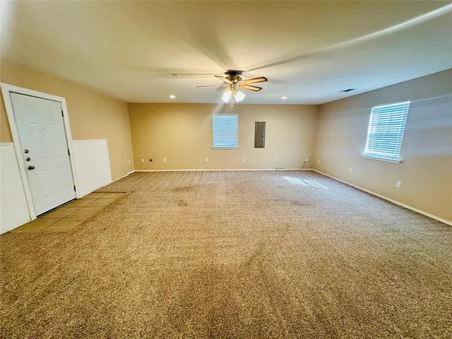 an empty room with a ceiling fan and window