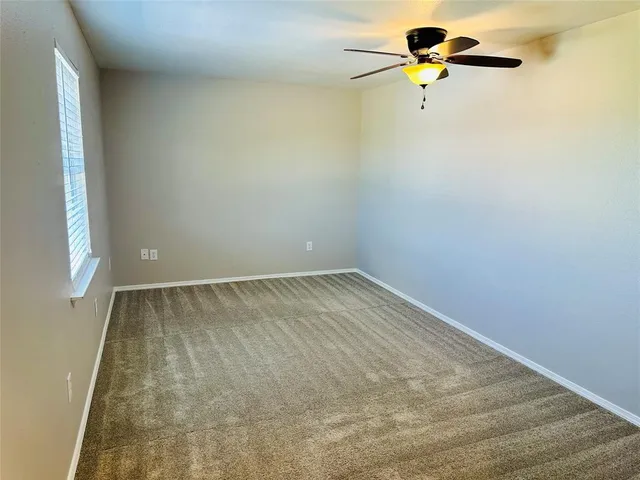 an empty room with a window and a ceiling fan