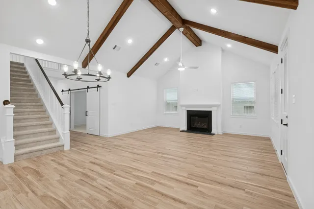 a view of an empty room with wooden floor fireplace and a window