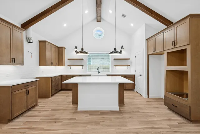 a large kitchen with a large counter top a sink stainless steel appliances and cabinets