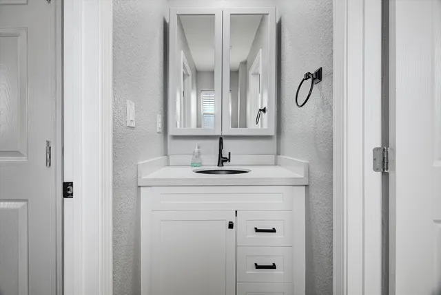 a bathroom with a granite countertop sink a mirror a vanity and a shower