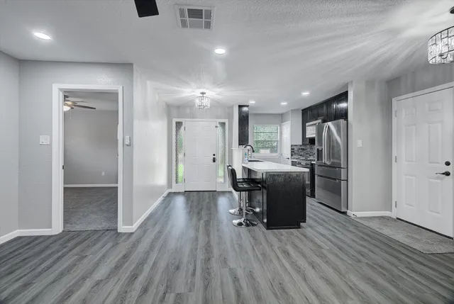 a kitchen with a refrigerator a sink and dishwasher with wooden floor