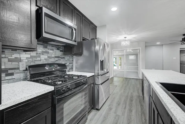 a view of an empty room with wooden floor and a ceiling fan
