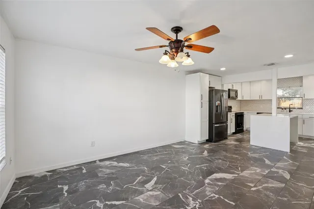 a view of a kitchen with a refrigerator a ceiling fan and a wooden floor