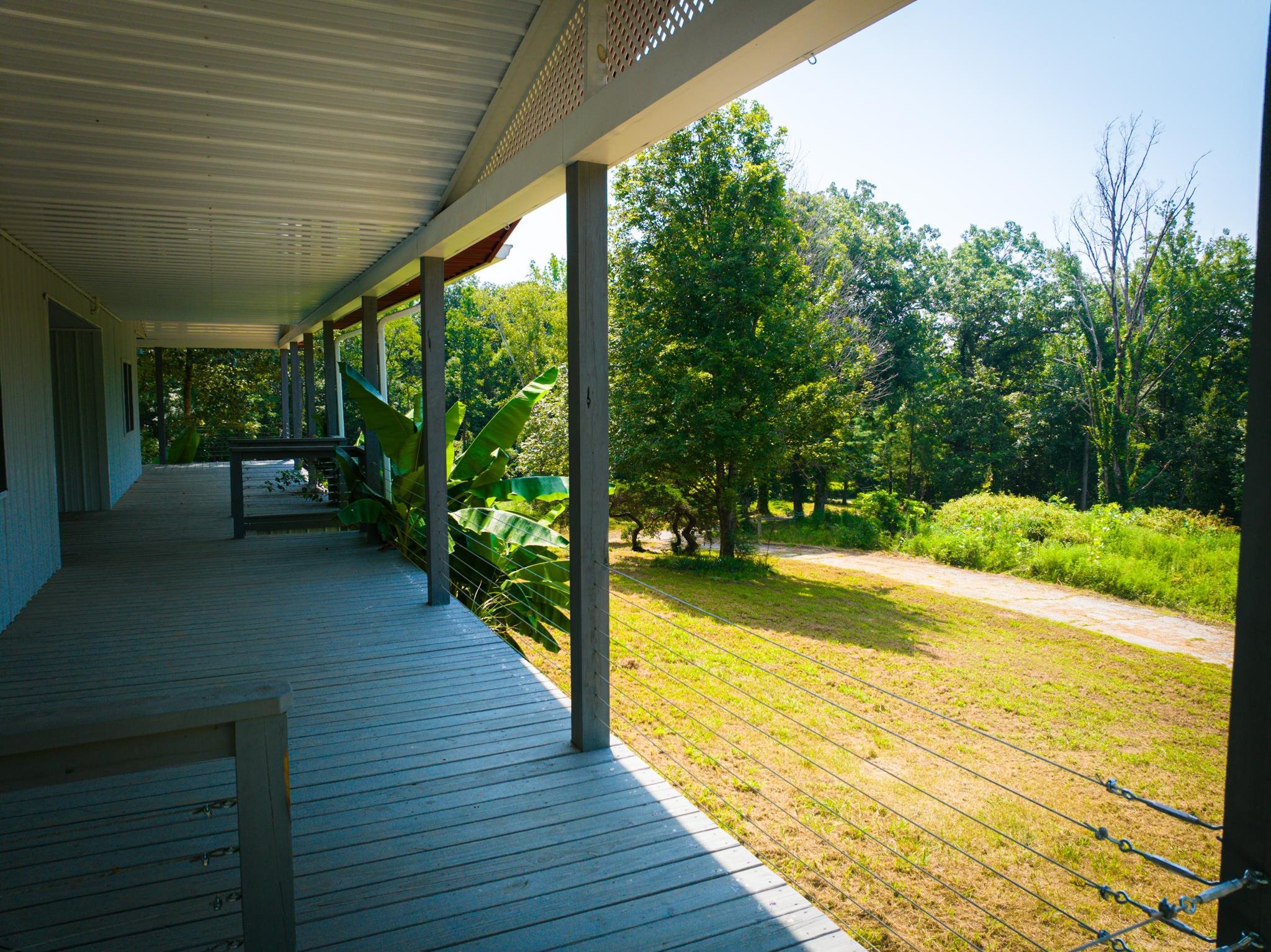 1421 Copper Spring Road Springville, TN 38256 - Photo 10 of 40 Expansive covered porch with wood-finish decking, cable railing, and a corrugated metal roof