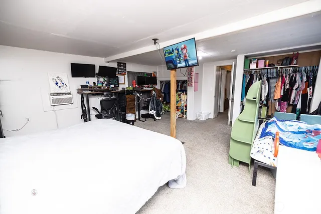 a bedroom with a bed a flat screen tv and dresser