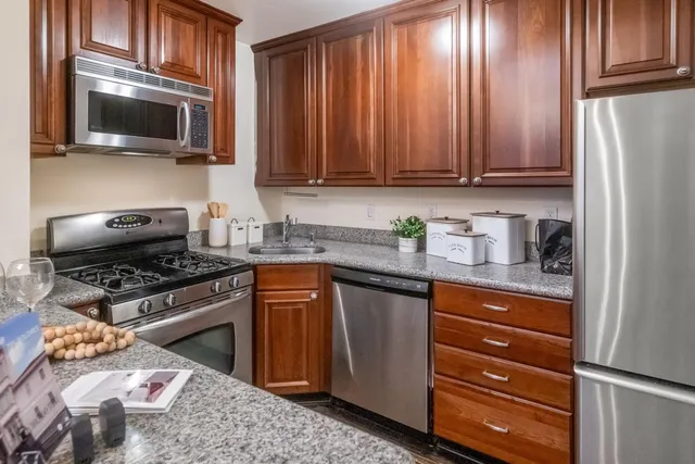 a kitchen with granite countertop wooden cabinets and stainless steel appliances