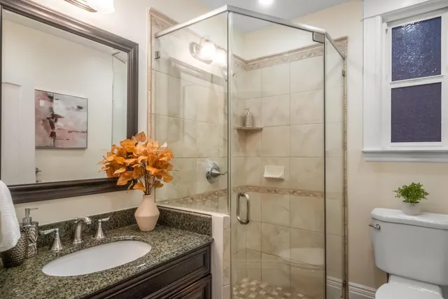 a bathroom with a granite countertop shower sink and mirror
