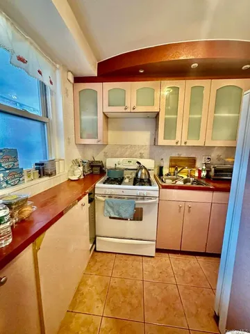 a white kitchen with stainless steel appliances granite countertop a stove and a sink